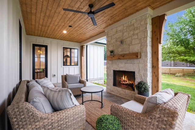 living room featuring wood ceiling, an outdoor stone fireplace, a ceiling fan, and stone finish flooring