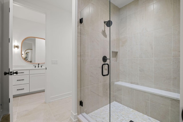 bathroom with a stall shower, baseboards, and vanity