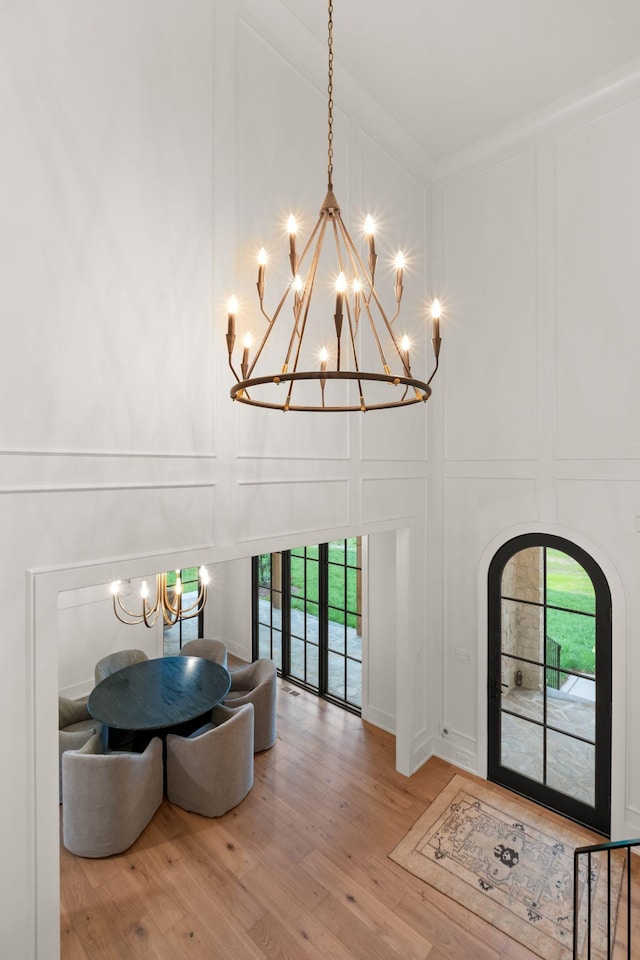 foyer entrance featuring an inviting chandelier, a wealth of natural light, a decorative wall, and a high ceiling