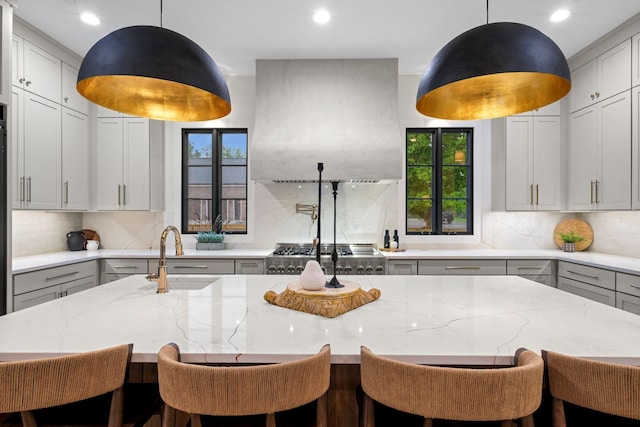 kitchen with backsplash, a wealth of natural light, light stone countertops, and a sink