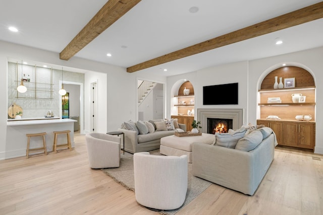living room featuring stairway, light wood-style flooring, a lit fireplace, and recessed lighting