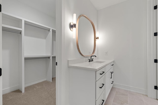 bathroom featuring baseboards, vanity, and a walk in closet