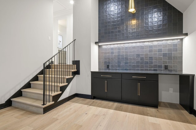 bar featuring light wood-style floors, tasteful backsplash, baseboards, and stairs