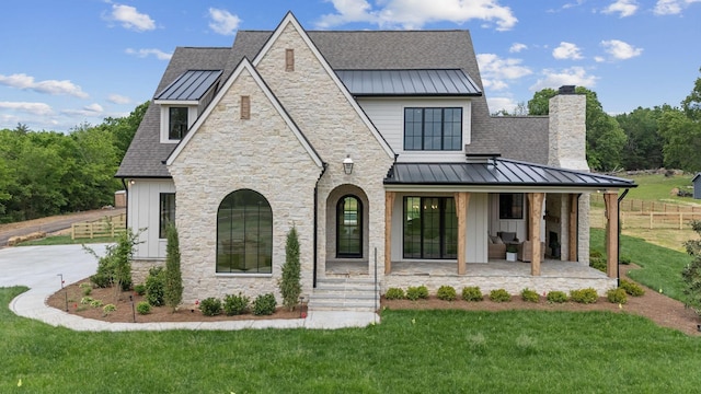 back of house featuring a lawn, a chimney, metal roof, and a standing seam roof