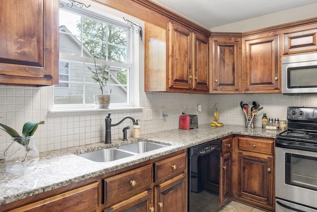 kitchen featuring light stone counters, stainless steel appliances, decorative backsplash, and a sink