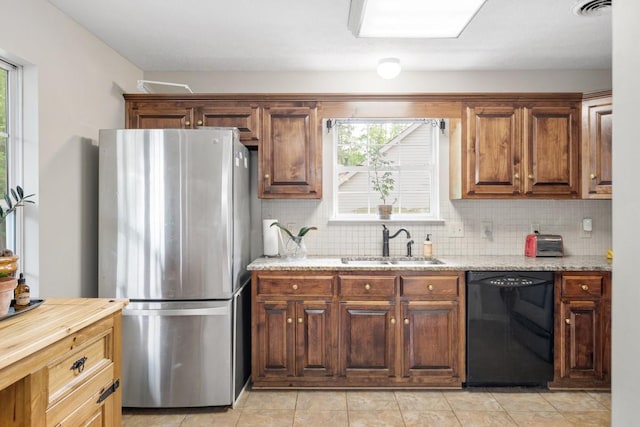 kitchen with freestanding refrigerator, black dishwasher, plenty of natural light, and a sink