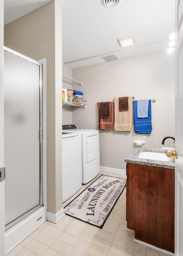 washroom with baseboards, laundry area, washer and dryer, and a sink