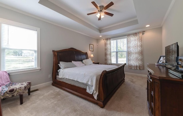 bedroom featuring light colored carpet, ornamental molding, ceiling fan, a tray ceiling, and baseboards
