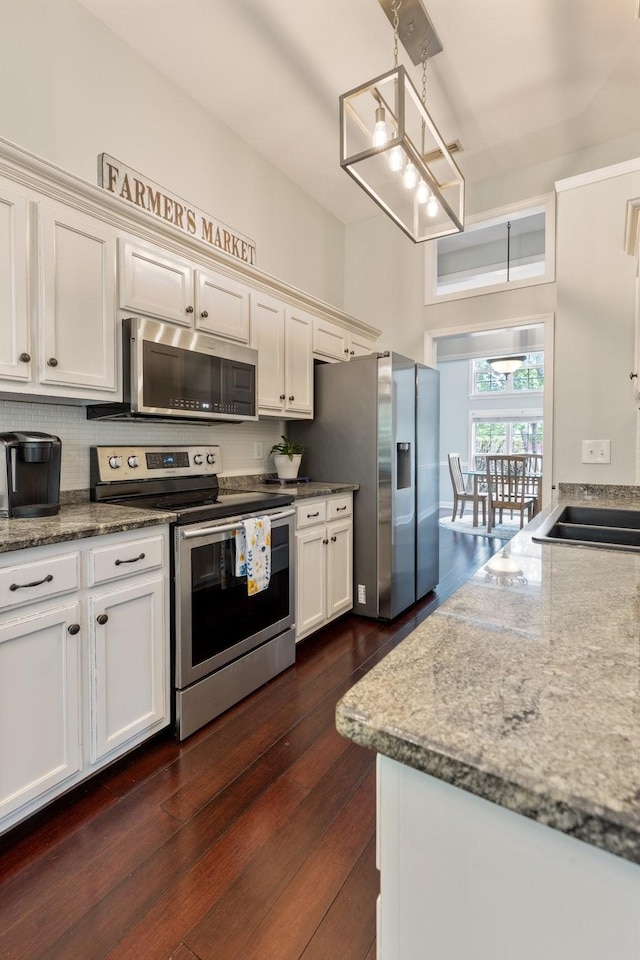 kitchen featuring light stone counters, stainless steel appliances, dark wood finished floors, and white cabinets