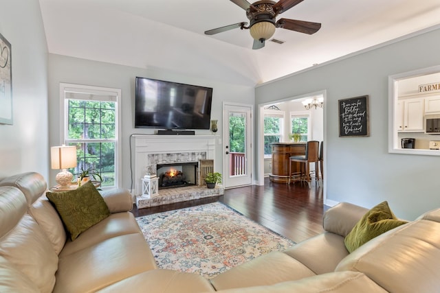 living area with a brick fireplace, hardwood / wood-style floors, plenty of natural light, and ceiling fan with notable chandelier