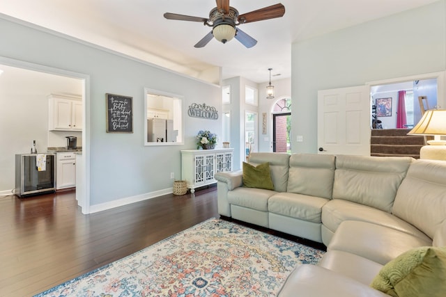 living room with dark wood-style flooring, baseboards, a ceiling fan, and beverage cooler