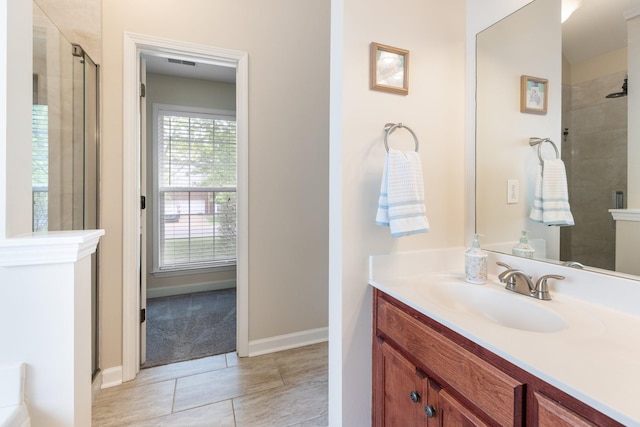 bathroom featuring a tile shower, visible vents, baseboards, tile patterned flooring, and vanity