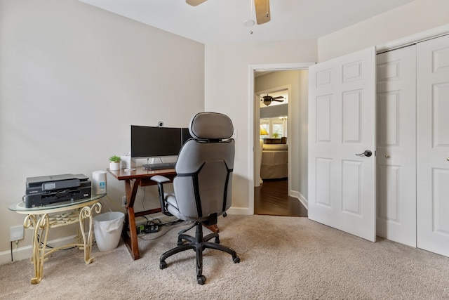 carpeted office with baseboards and a ceiling fan