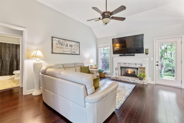 living area featuring a brick fireplace, lofted ceiling, ceiling fan, and dark wood-style floors