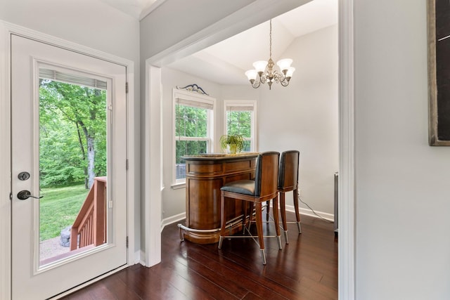dining space featuring baseboards, a notable chandelier, a healthy amount of sunlight, and dark wood-type flooring