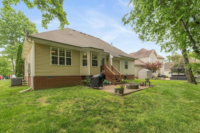 rear view of house featuring crawl space, a storage unit, an outbuilding, a lawn, and an outdoor fire pit