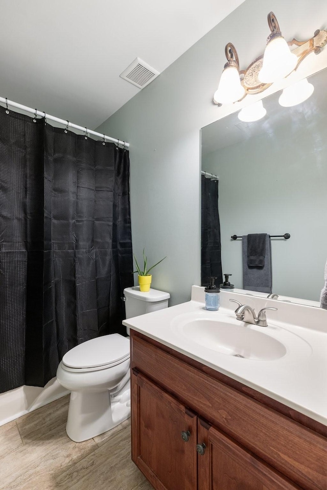full bathroom featuring toilet, vanity, visible vents, and wood finished floors