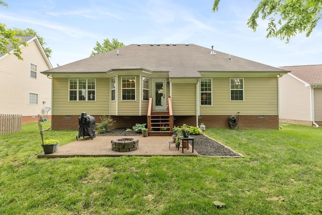 rear view of property featuring roof with shingles, a patio area, a fire pit, crawl space, and a lawn