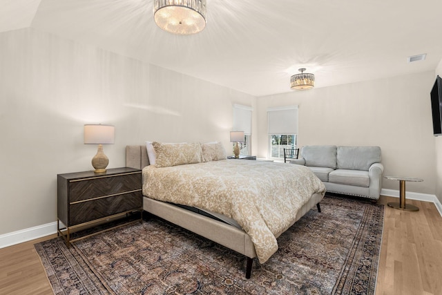 bedroom featuring baseboards, visible vents, and wood finished floors