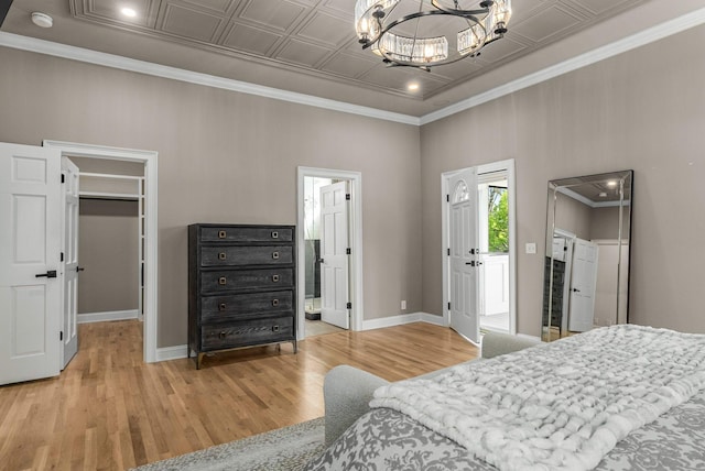 bedroom with baseboards, a spacious closet, a chandelier, and wood finished floors