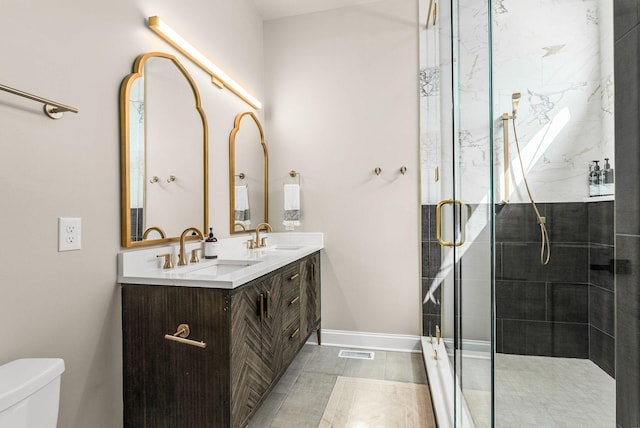 bathroom with toilet, visible vents, a shower stall, and a sink