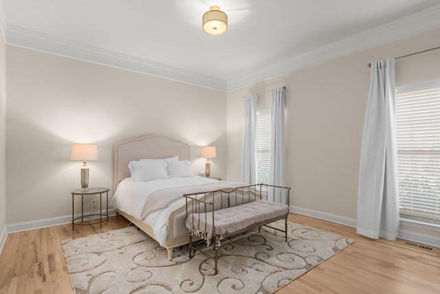 bedroom with visible vents, wood finished floors, baseboards, and ornamental molding