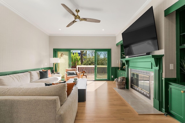 living room featuring a tile fireplace, light wood finished floors, a ceiling fan, ornamental molding, and recessed lighting