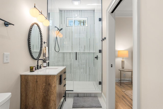 bathroom with baseboards, toilet, a shower stall, vanity, and wood finished floors