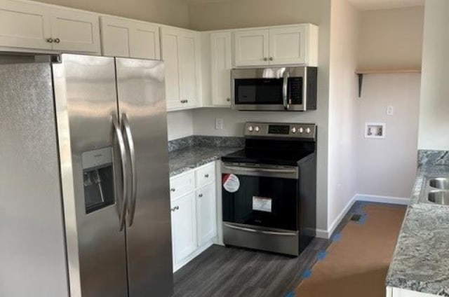 kitchen featuring stone counters, baseboards, dark wood finished floors, white cabinetry, and stainless steel appliances