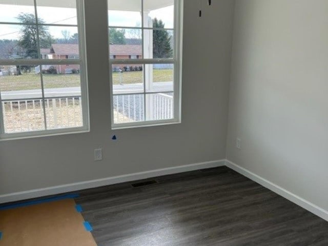 empty room with dark wood finished floors and baseboards
