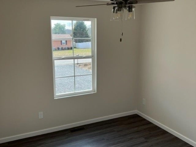 unfurnished dining area with a ceiling fan, baseboards, and dark wood finished floors