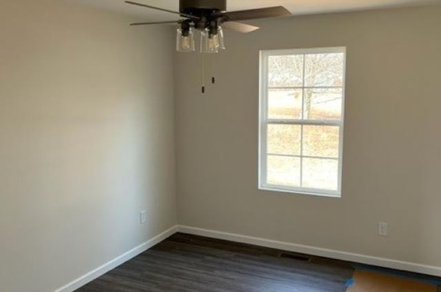 spare room featuring a ceiling fan, baseboards, a healthy amount of sunlight, and dark wood-type flooring