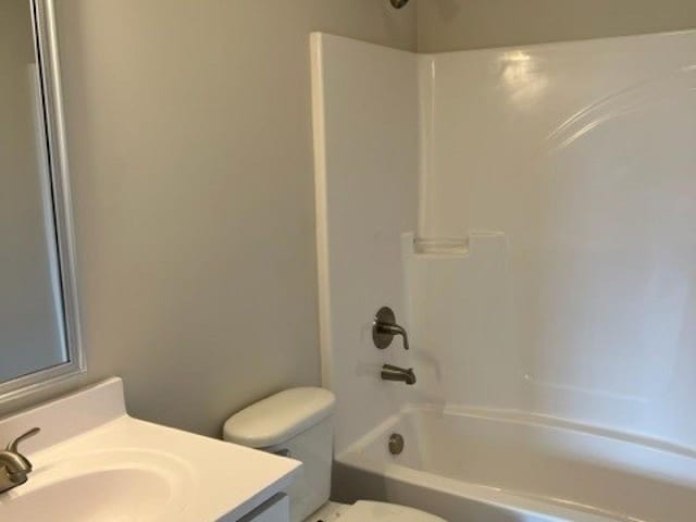 bathroom featuring toilet, vanity, and shower / washtub combination