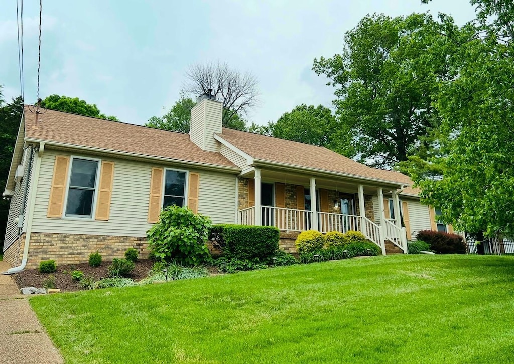 single story home featuring a chimney, a porch, and a front lawn