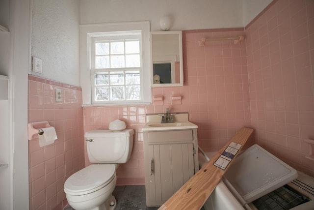 bathroom featuring tile walls, toilet, wainscoting, and vanity