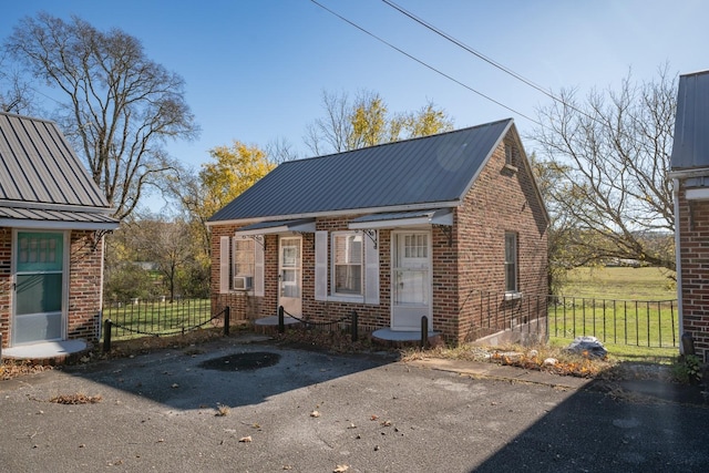 exterior space featuring metal roof, brick siding, and fence