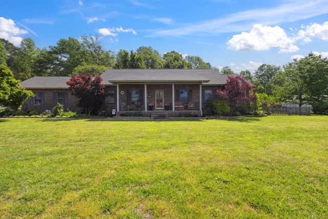 view of front of home with fence, a sunroom, brick siding, and a front yard