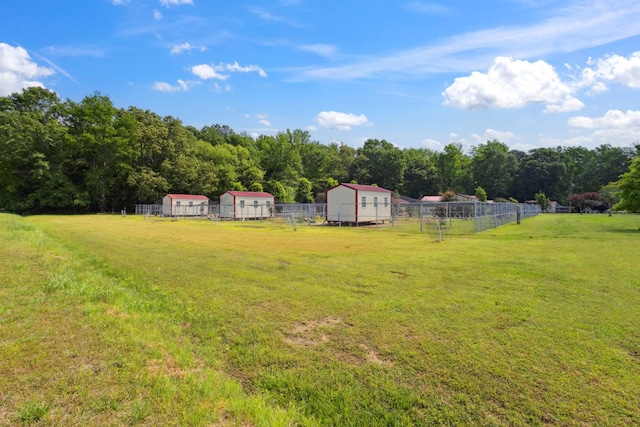 view of yard with a shed, fence, and an outbuilding