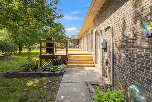 view of side of property featuring a yard, a deck, and brick siding