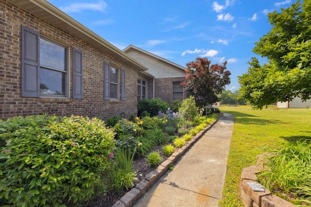 view of side of home with a lawn and brick siding