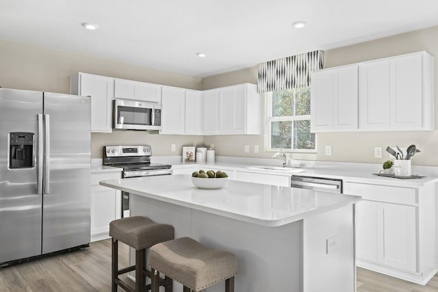 kitchen featuring a breakfast bar area, a center island, a sink, white cabinetry, and stainless steel appliances