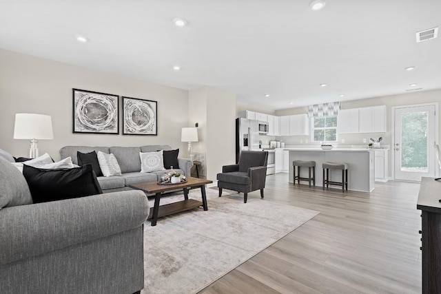 living room featuring visible vents, light wood-style flooring, and recessed lighting