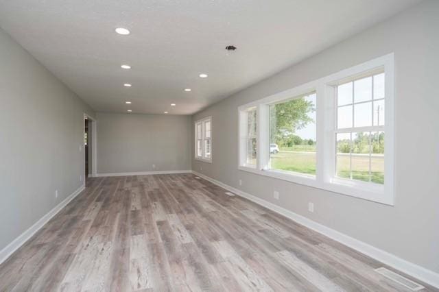 empty room with baseboards, light wood finished floors, and recessed lighting