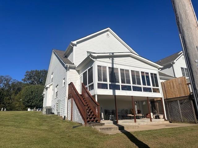 rear view of property featuring a lawn, cooling unit, a patio area, stairs, and a sunroom