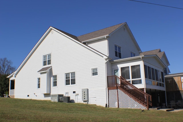 back of house with stairway, a sunroom, central AC, and a lawn