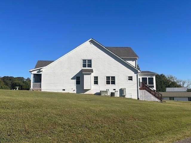 back of property featuring central air condition unit, stairway, and a lawn