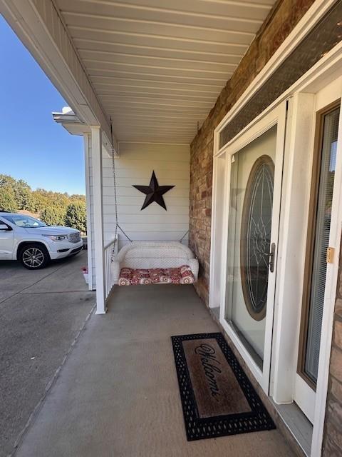 property entrance with covered porch and stone siding