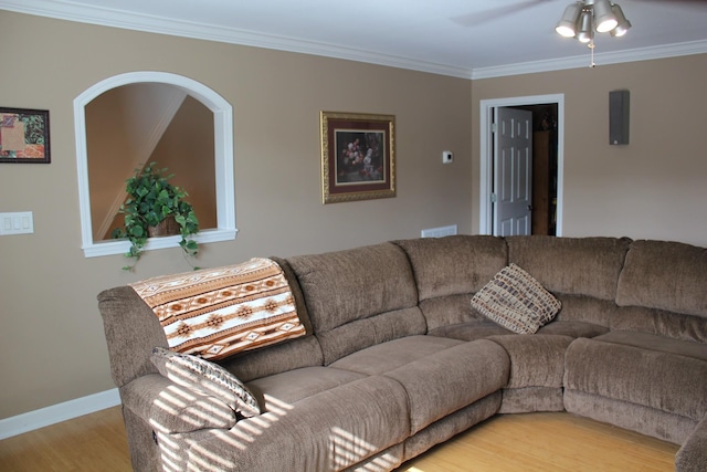 living area featuring a ceiling fan, baseboards, ornamental molding, visible vents, and light wood-type flooring