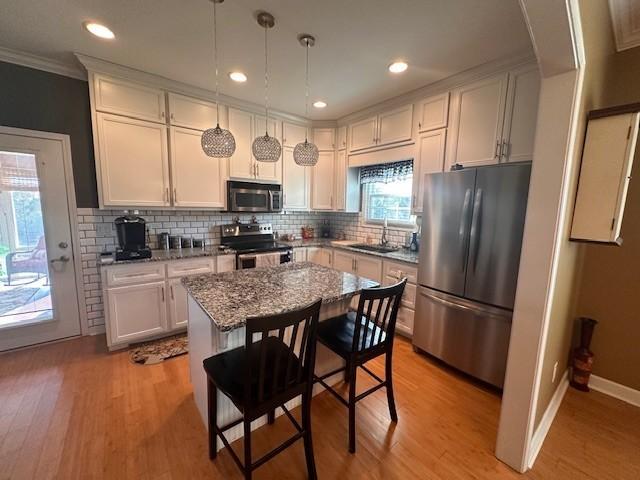 kitchen with a sink, stainless steel appliances, tasteful backsplash, dark stone counters, and crown molding