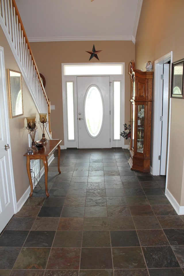 foyer with ornamental molding, stairs, baseboards, and stone tile flooring